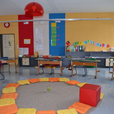 Bild vergrößern: Ein Sitzkreis aus Kissen liegt auf dem Boden des Klassenzimmers.