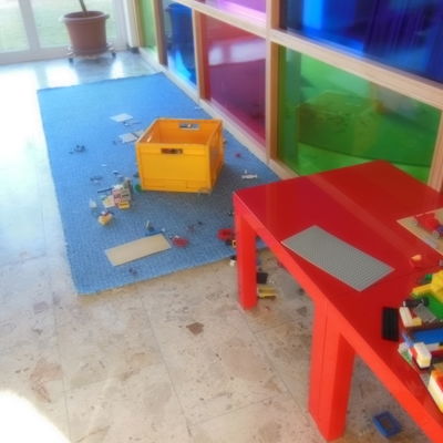 Bild vergrößern: Ein roter Spieltisch und Spielsachen, die auf dem Boden liegen